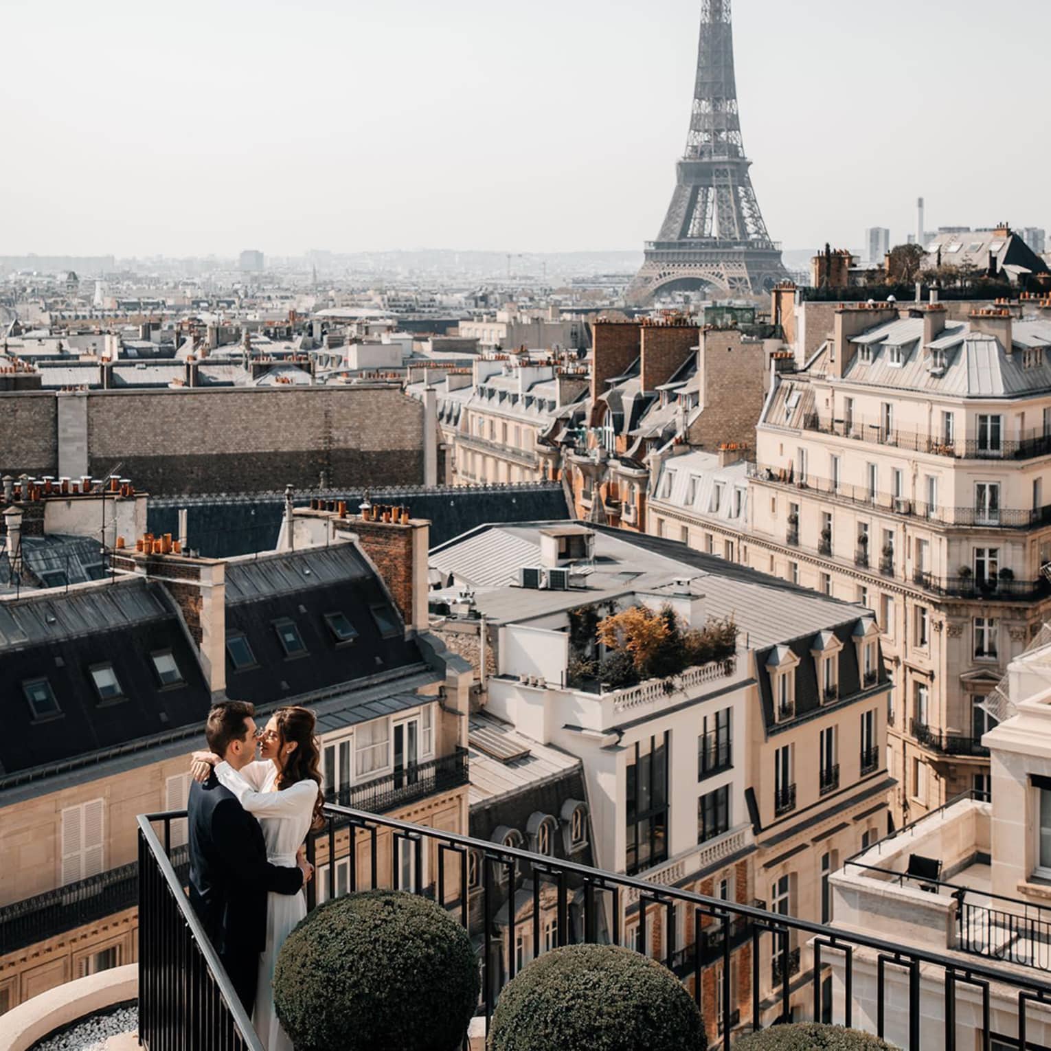 Couple embracing on Paris Hotel terrace with Eiffel Tower view