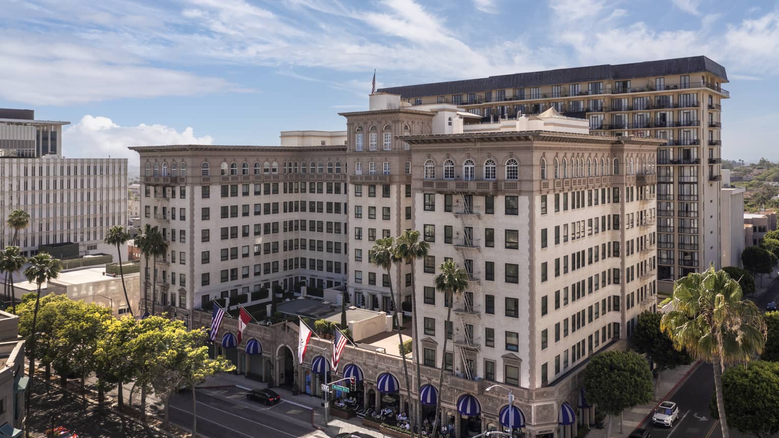 The exterior of a large stone building surrounded by streets and palm trees.