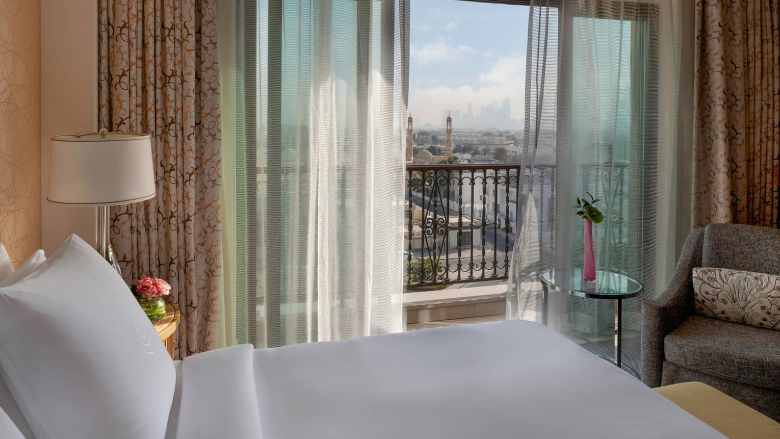 Bedroom with bed, armchair, curtain sheers and balcony