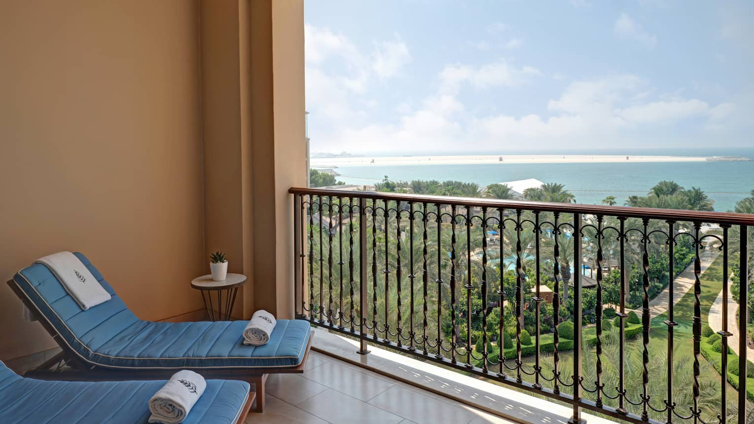 Private balcony with two blue lounge chairs, towels, sea view