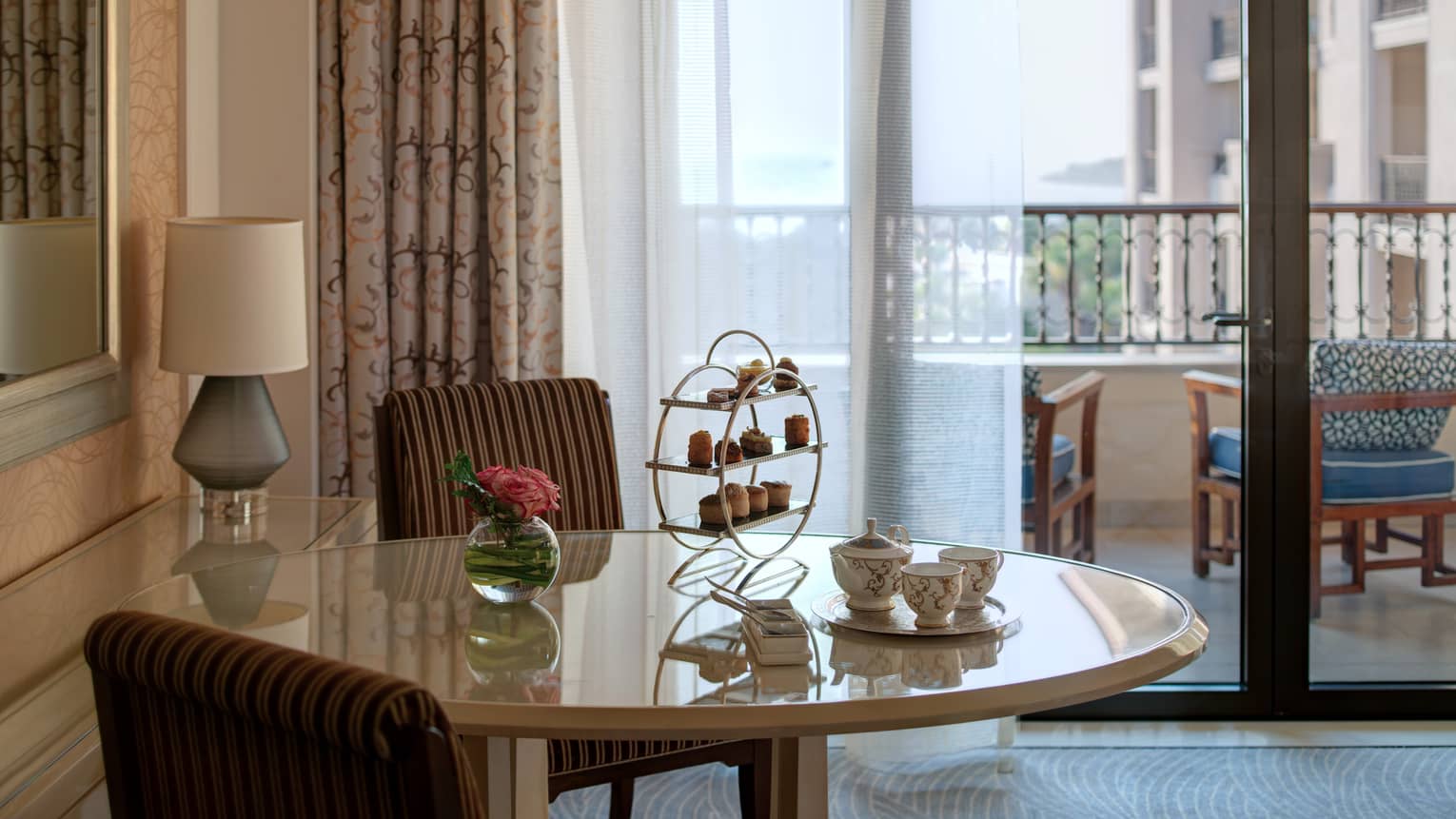 Round table and two cushioned chairs, balcony in the distance