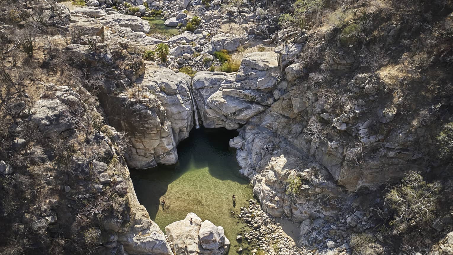 A waterfall and small pond surrounded by rocky cliffs.