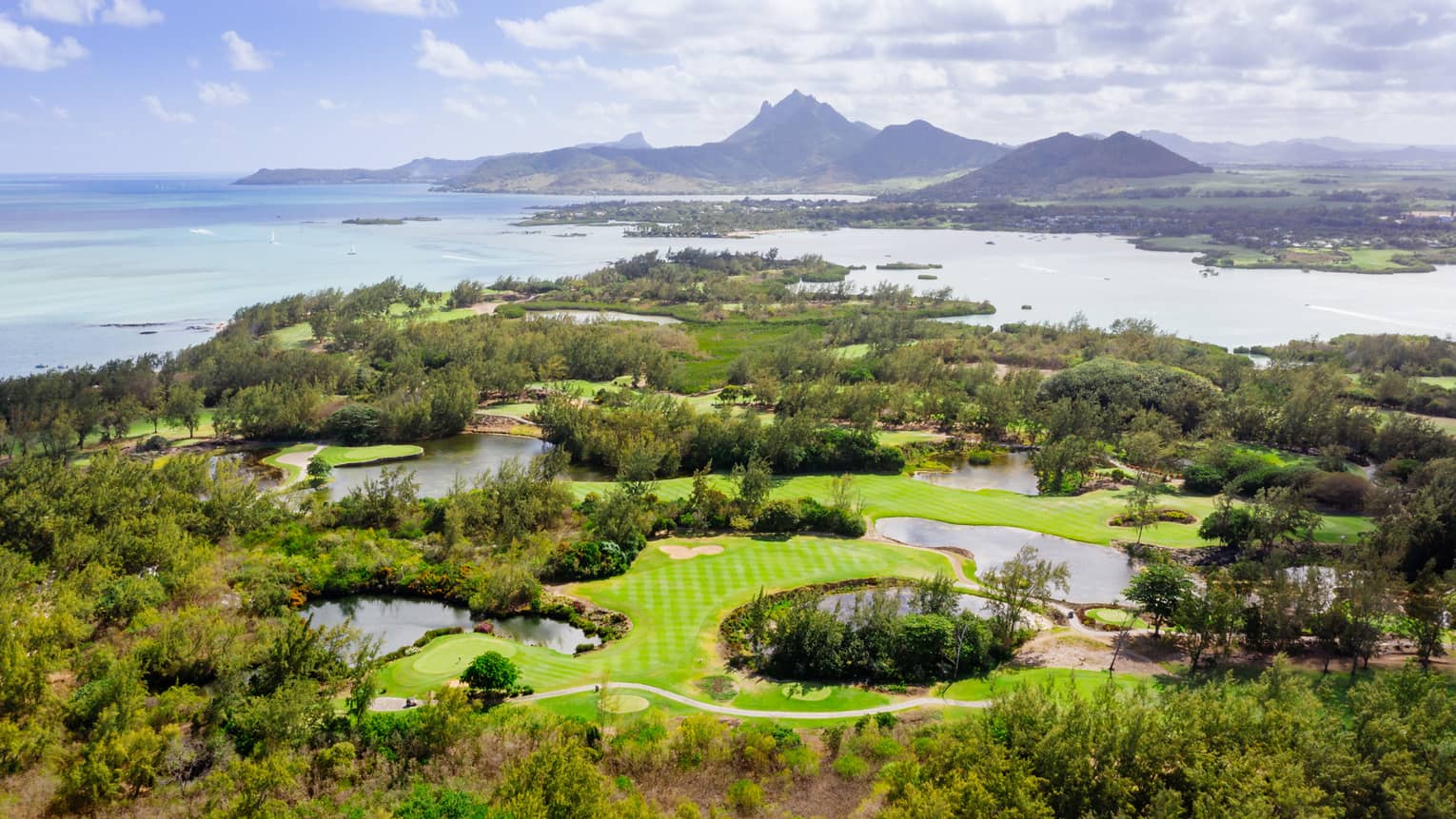 Aerial view of golf course with Indian Ocean and mountains in backdrop