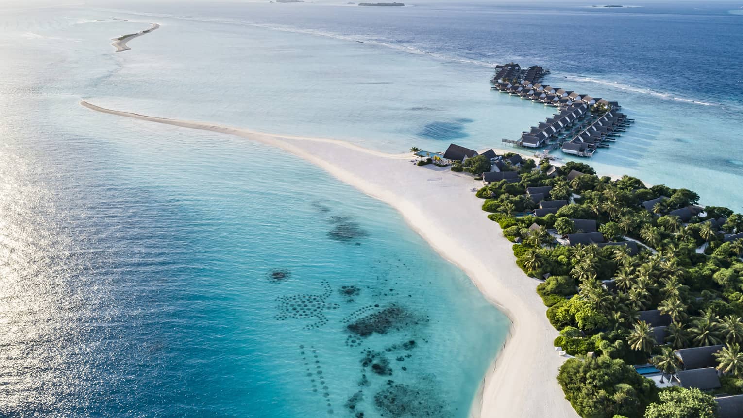 This image depicts a white sand beach, lush greenery and turquoise blue water at the beautiful Four Seasons Resort Maldives at Landaa Giraavaru – home to many outstanding ESG initiatives.