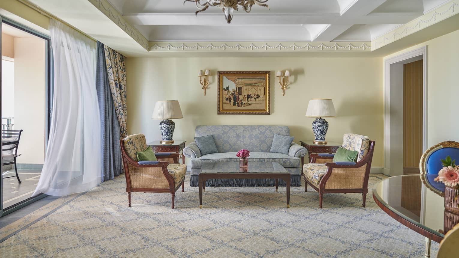 Deluxe Two Bedroom Suite living area with couch, twin armchairs and coffee table, sliding glass door to veranda