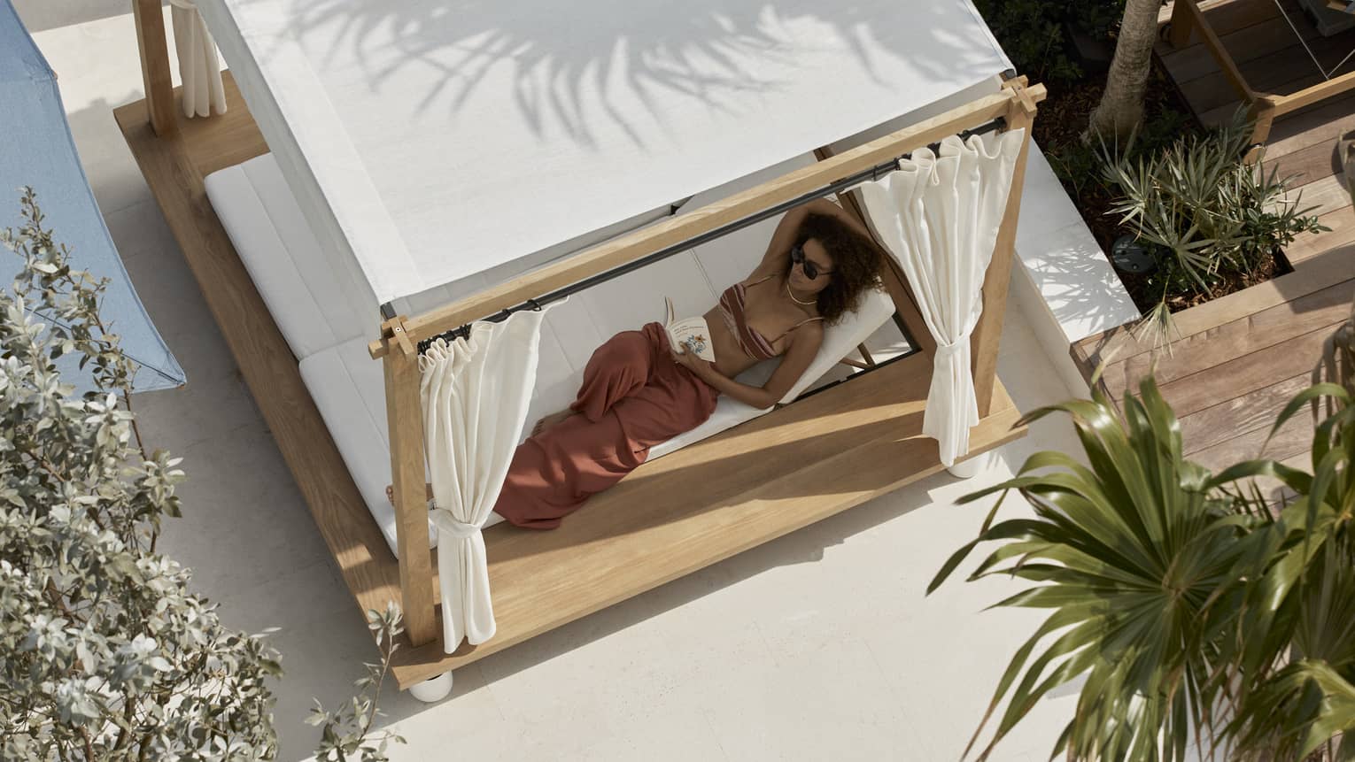 Aerial view of woman lounging in a covered poolside daybed