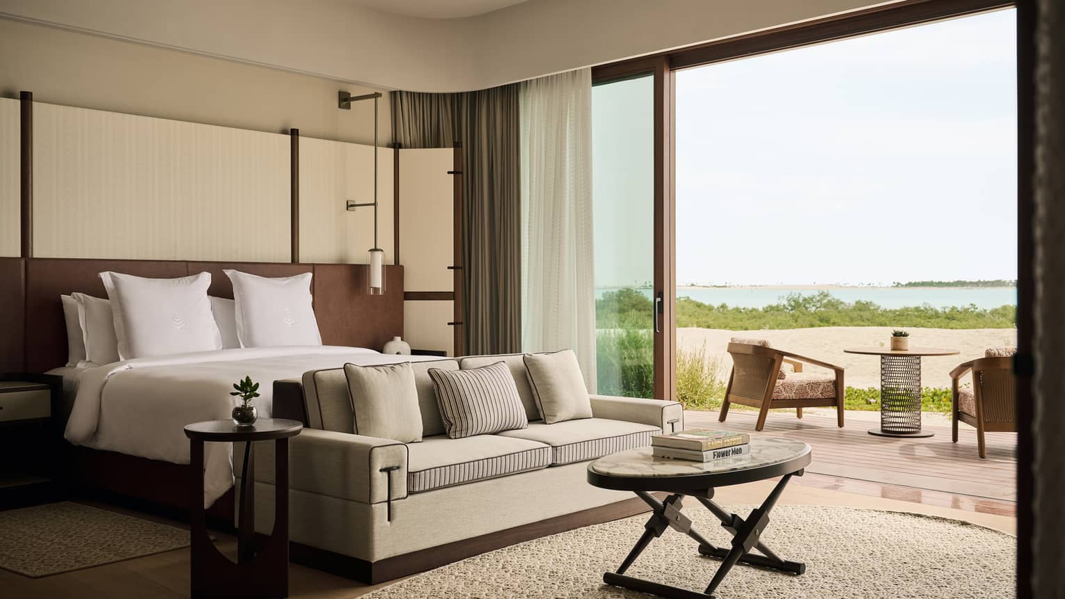 Large contemporary bedroom at a beachfront resort, featuring a king bed, sofa and walk-out, sea-view terrace