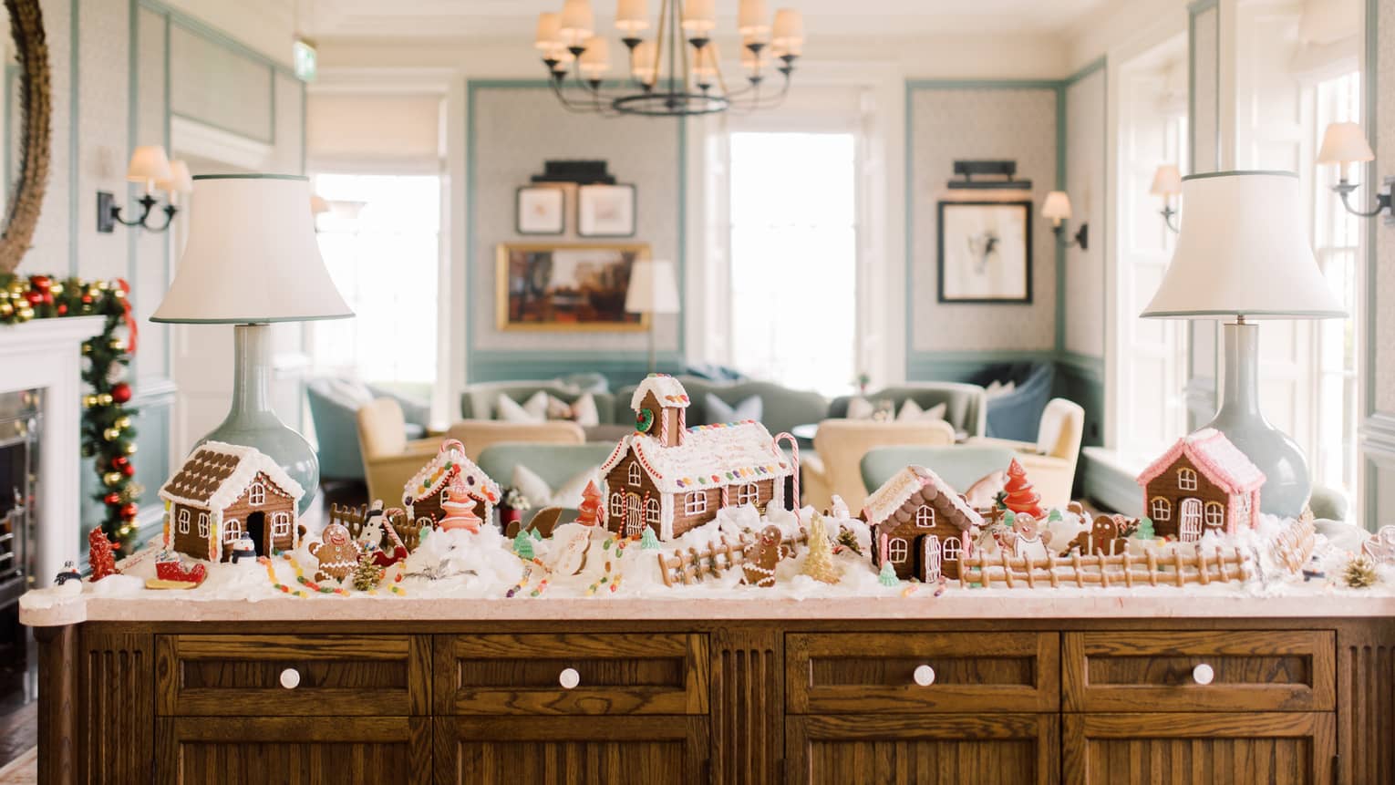 Guest room credenza decorated with gingerbread house village, flanked by two lamps