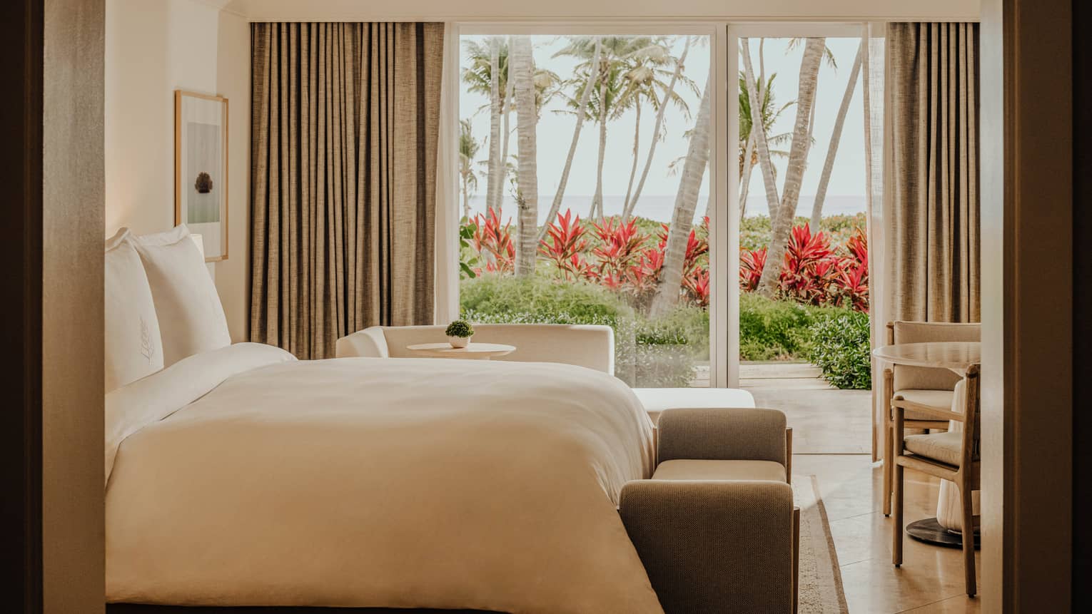 Guest room at a tropical resort, featuring a walk-out balcony with garden and ocean views