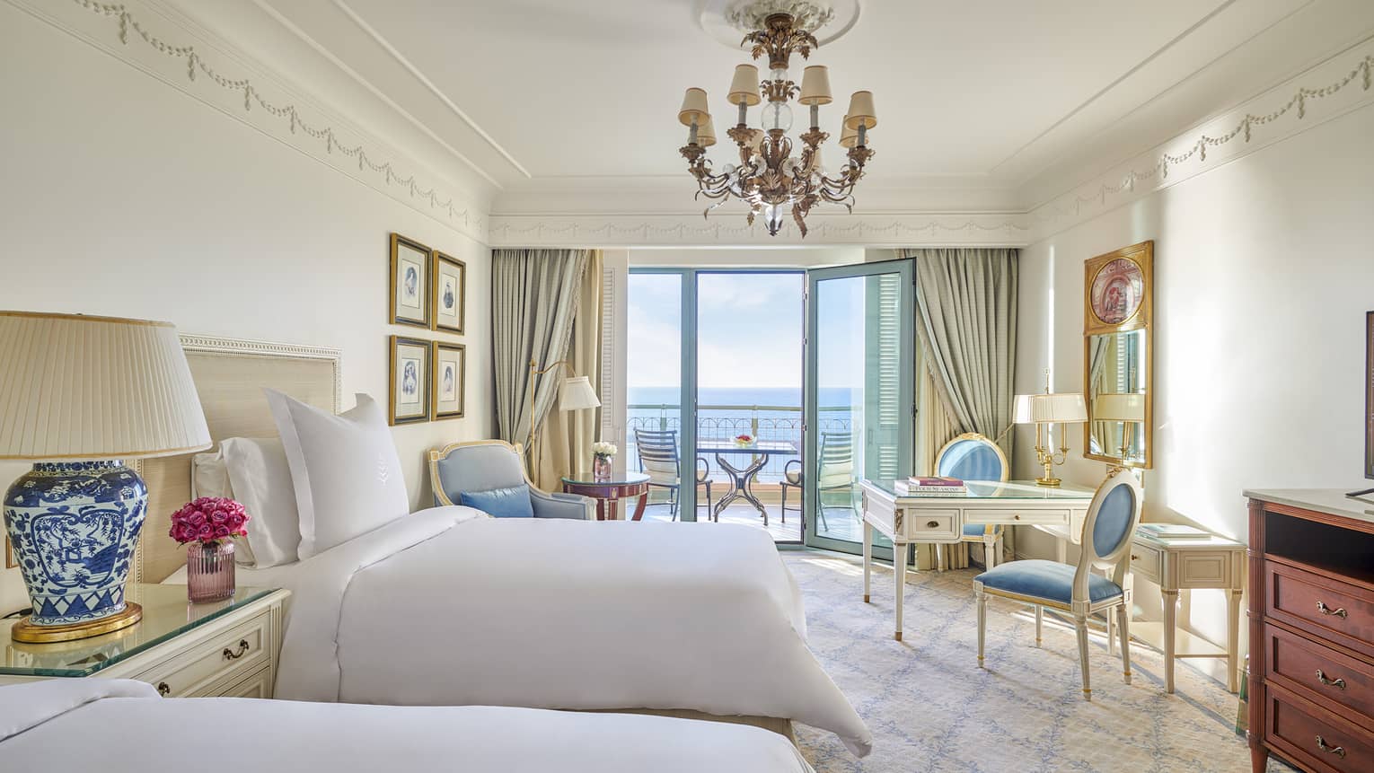 Sea View Room with twin beds, vanity table and two chairs, armchair, glass door to veranda
