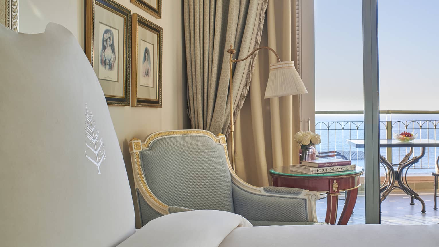 Sea View Room close-up of bed, armchair, side table, veranda with ocean views