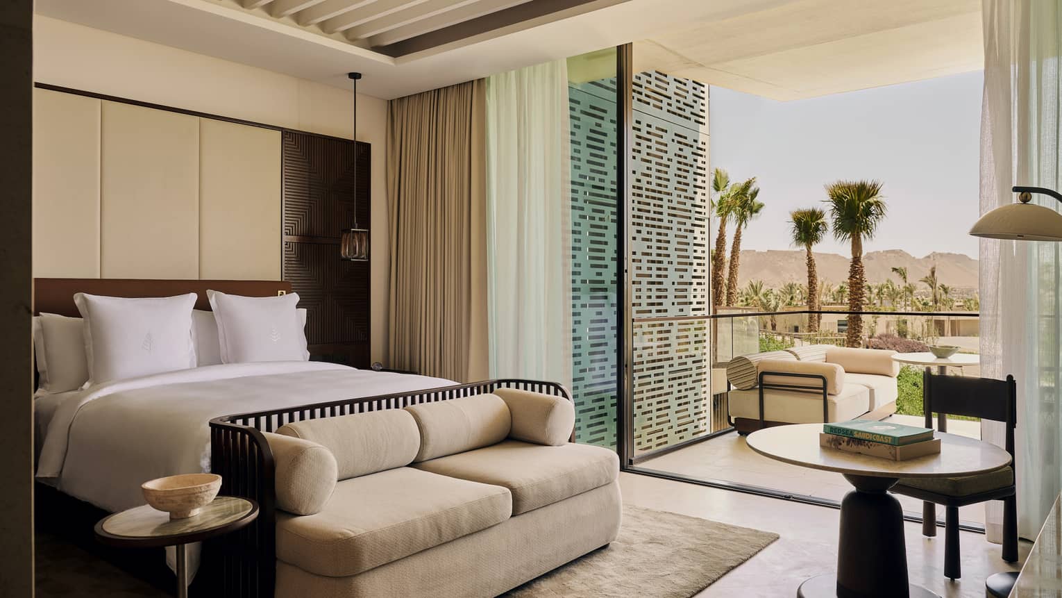 Luxury resort suite featuring a king bed, small sofa and walk-out terrace