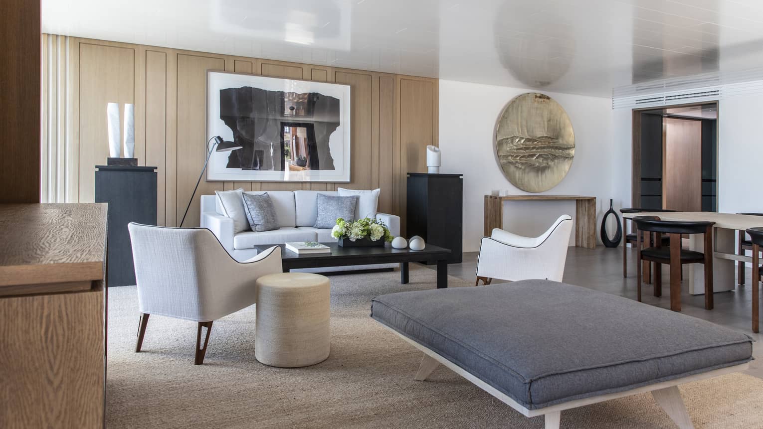 Beach-chic living room with a sofa, two arm chairs, a large ottoman with a grey cushion