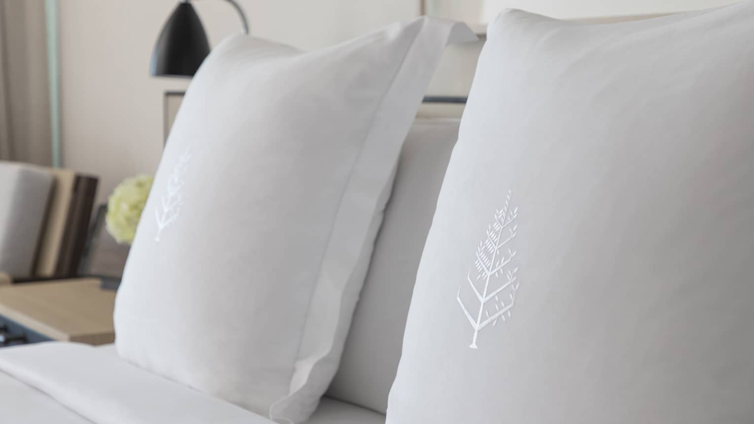 Two white sham pillows on bed with embroidered Four Seasons logos