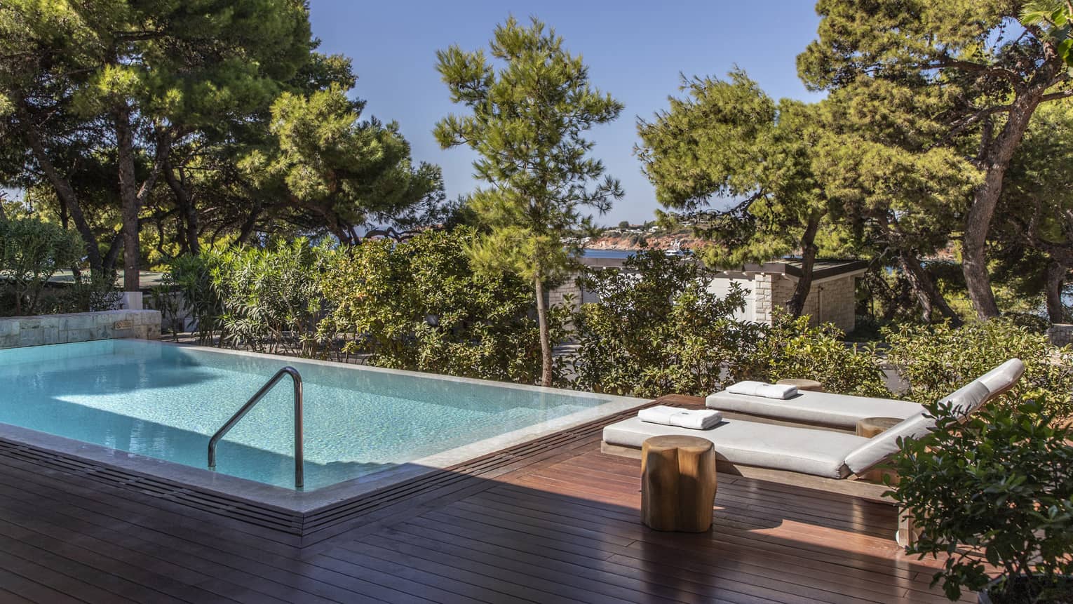 Wooden deck with two lounge chairs, pool, trees