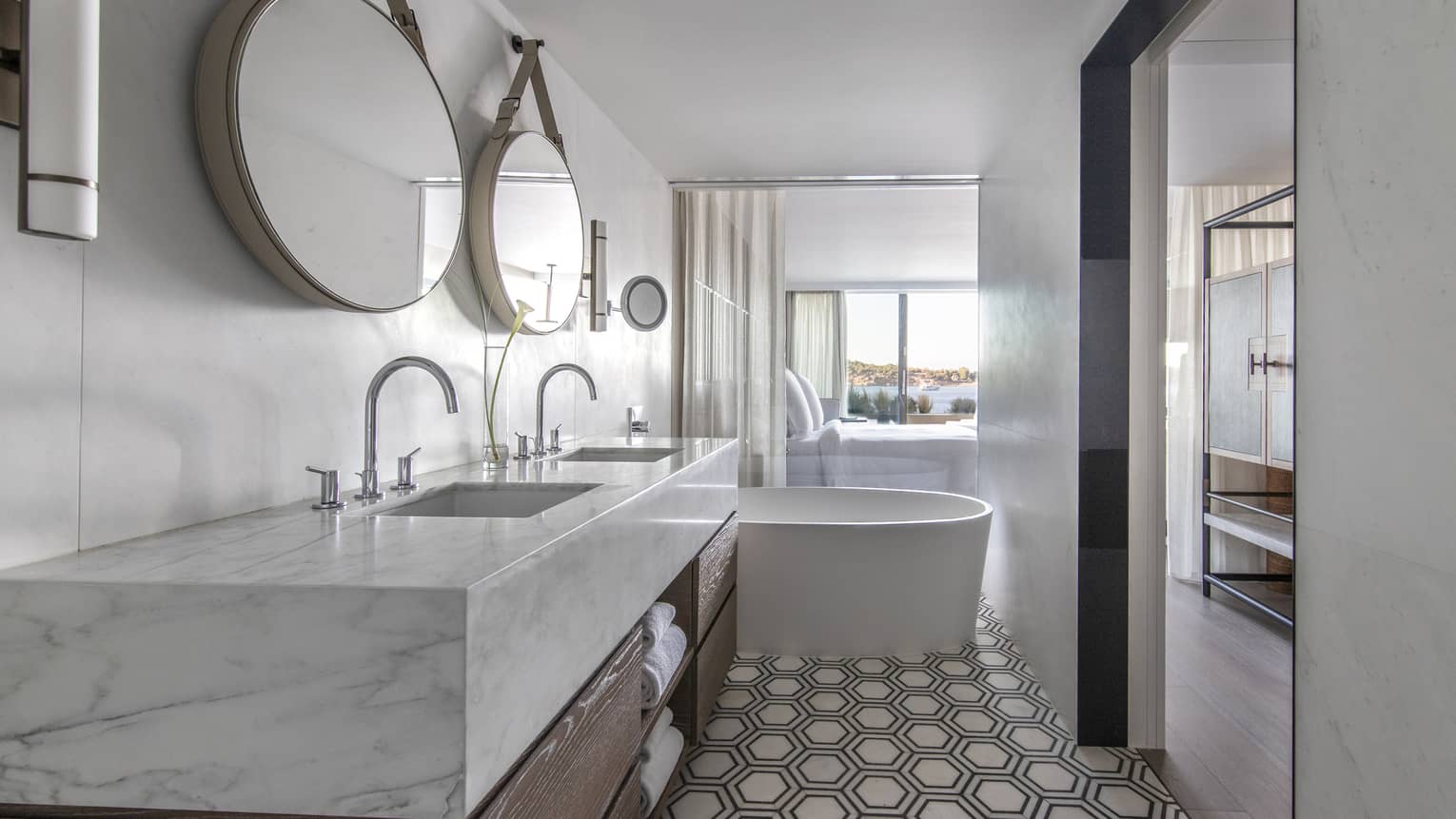 Bathroom with marble-topped double vanity, two round mirrors, tub