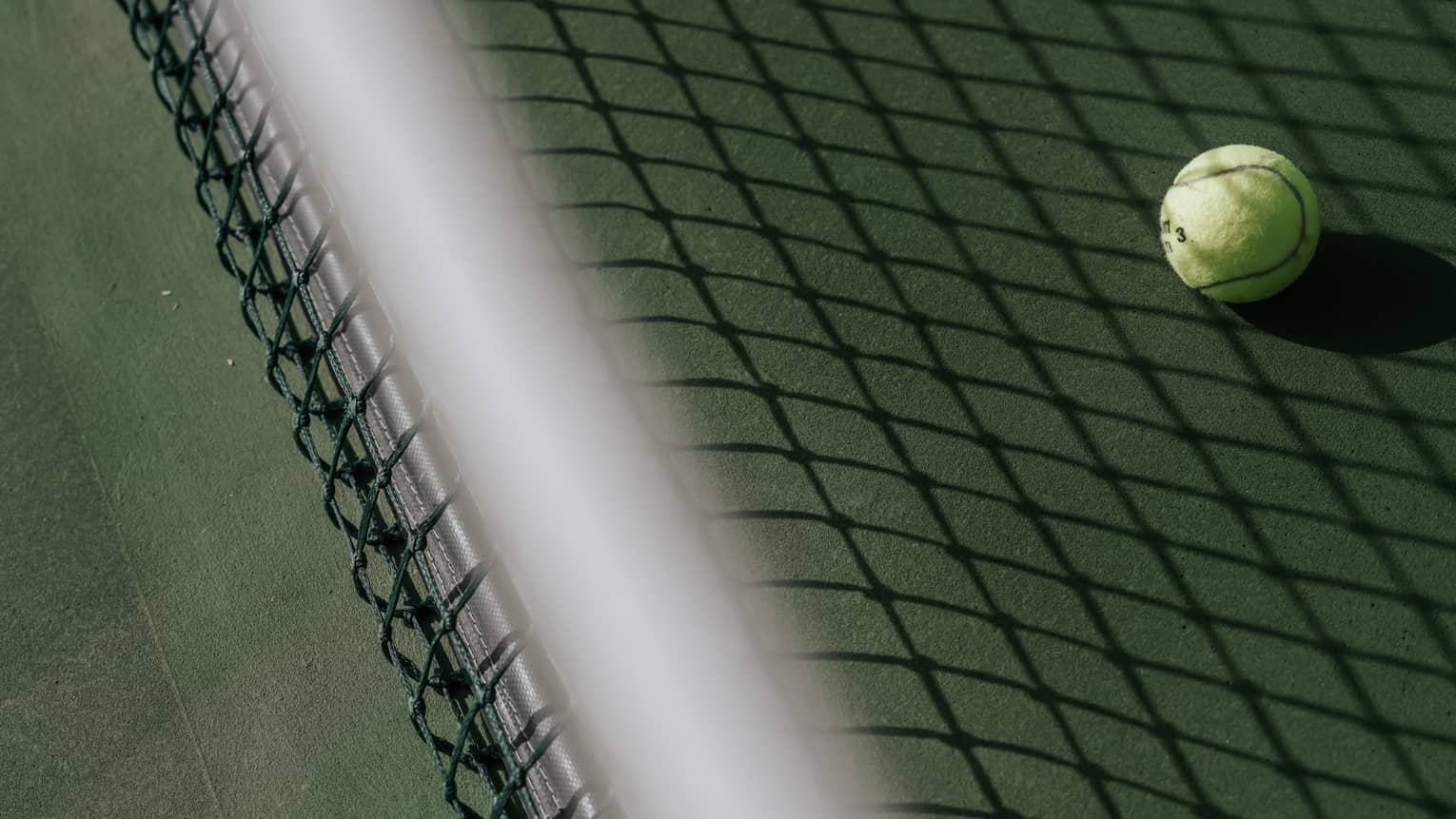 Tennis ball on tennis court with shadow of net