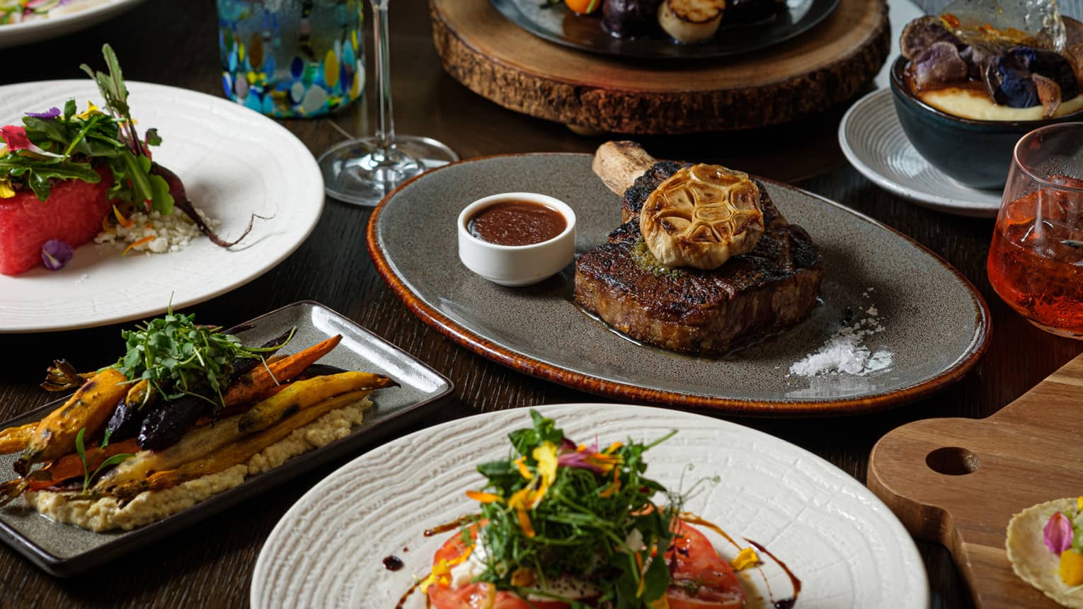 An assortment of food including steak, carrots, and tomatos.