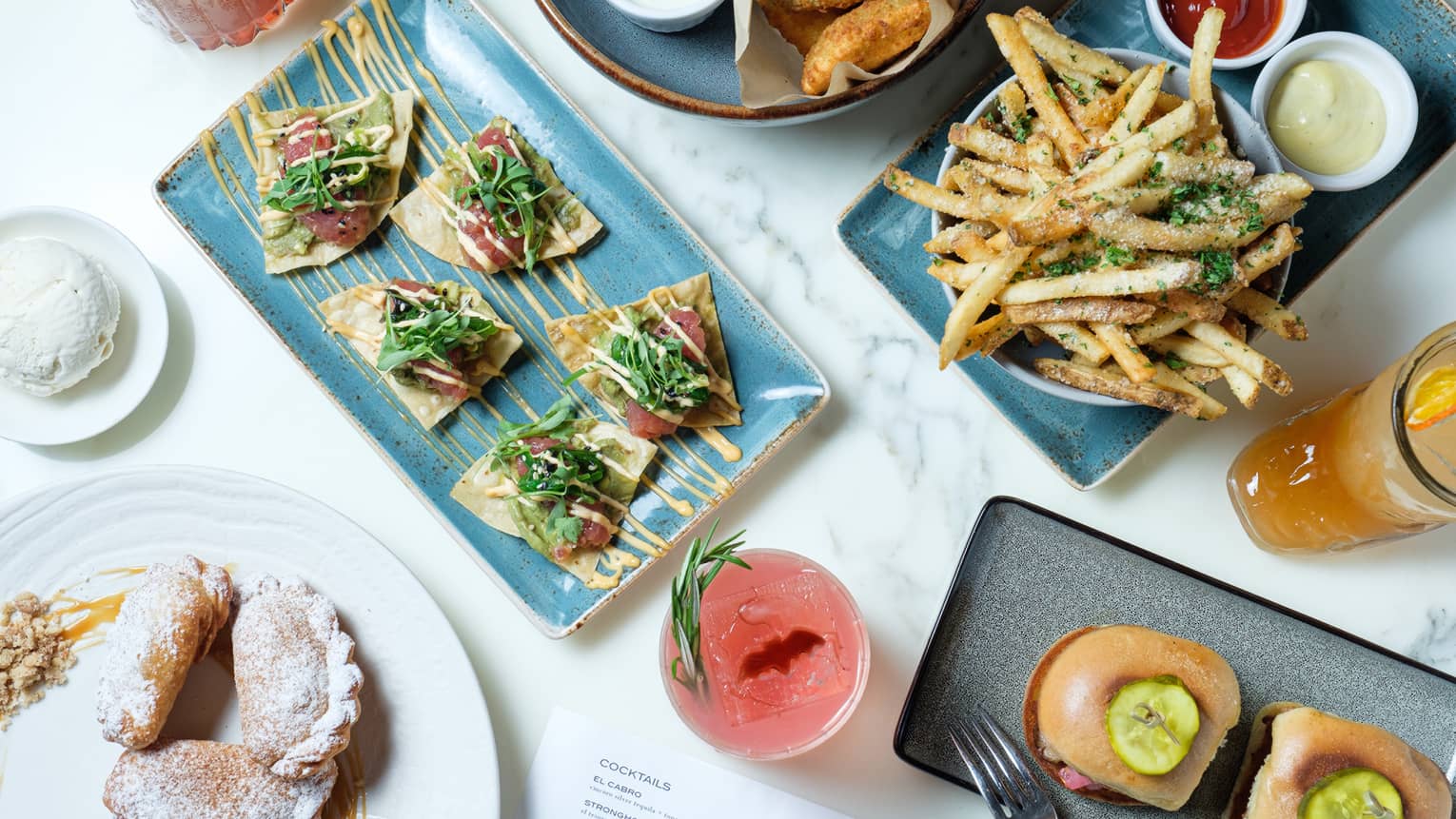 An assortment of food including tacos, burgers, fries, and chicken wings.
