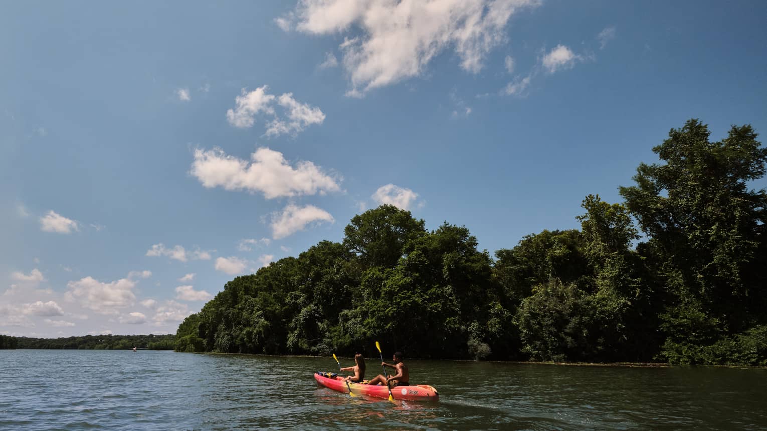 Two guests on a kayak using oars to move the kayak through the water