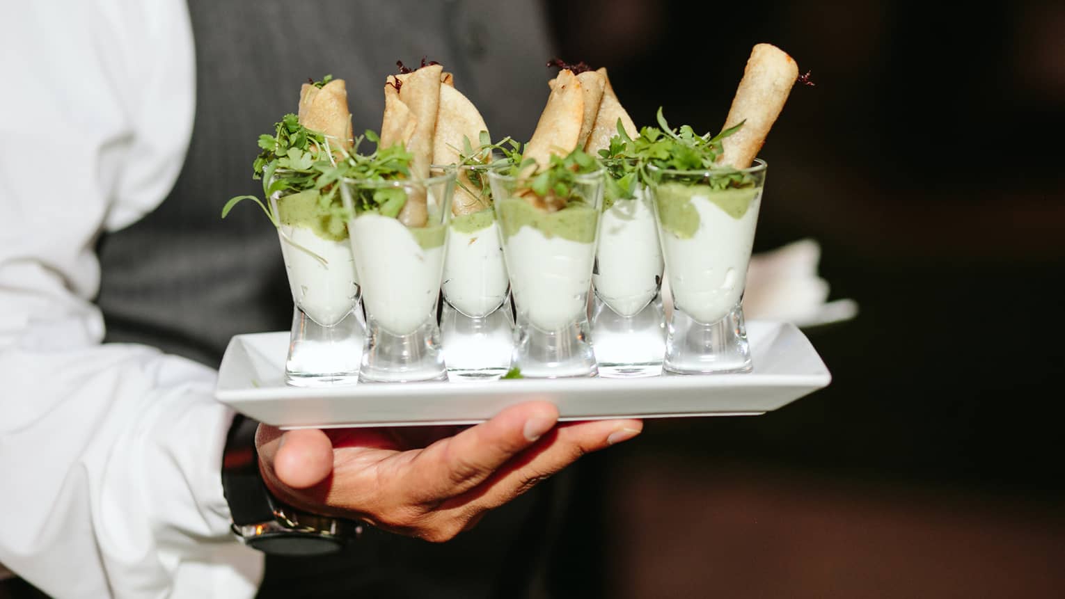 A staff member holding a plate for small foods to serve to guests.
