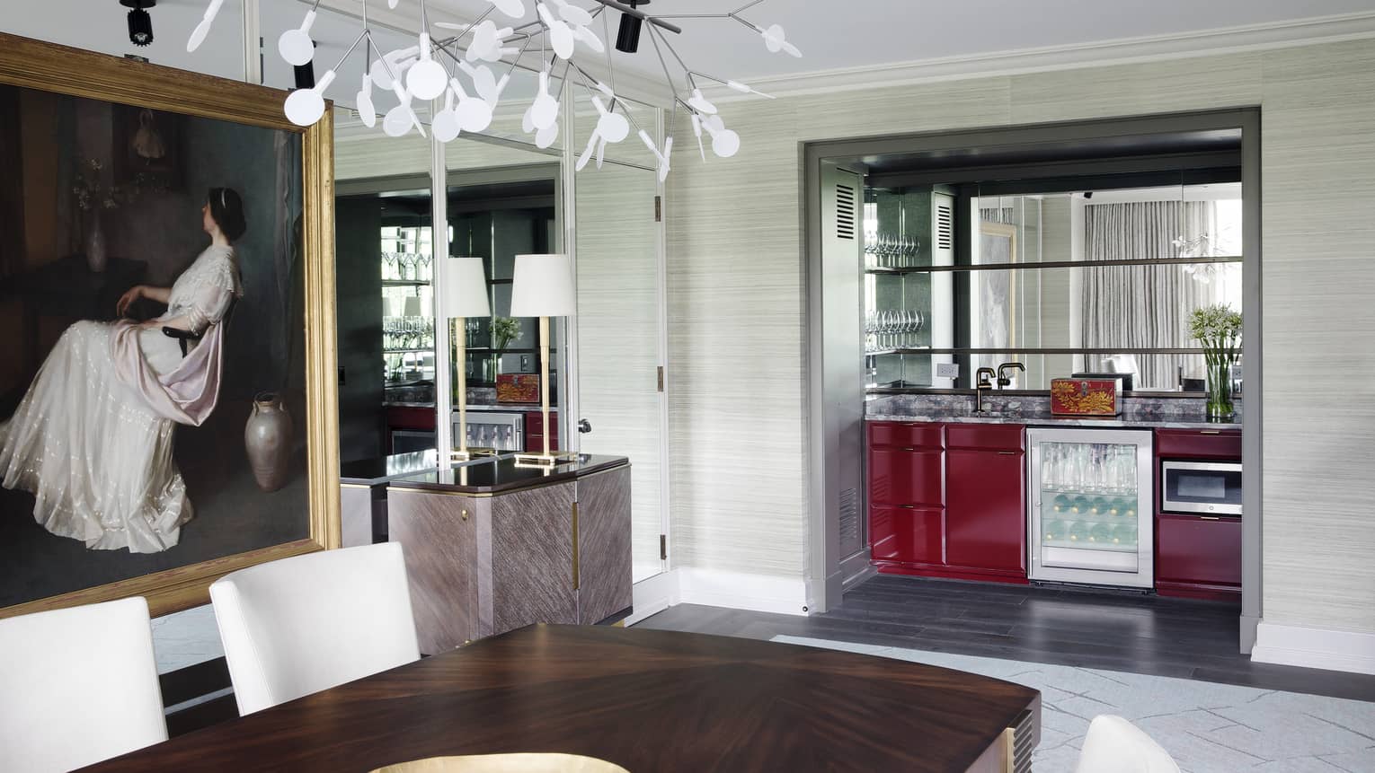 An abstract light fixture hangs over a dining room table and kitchenette 