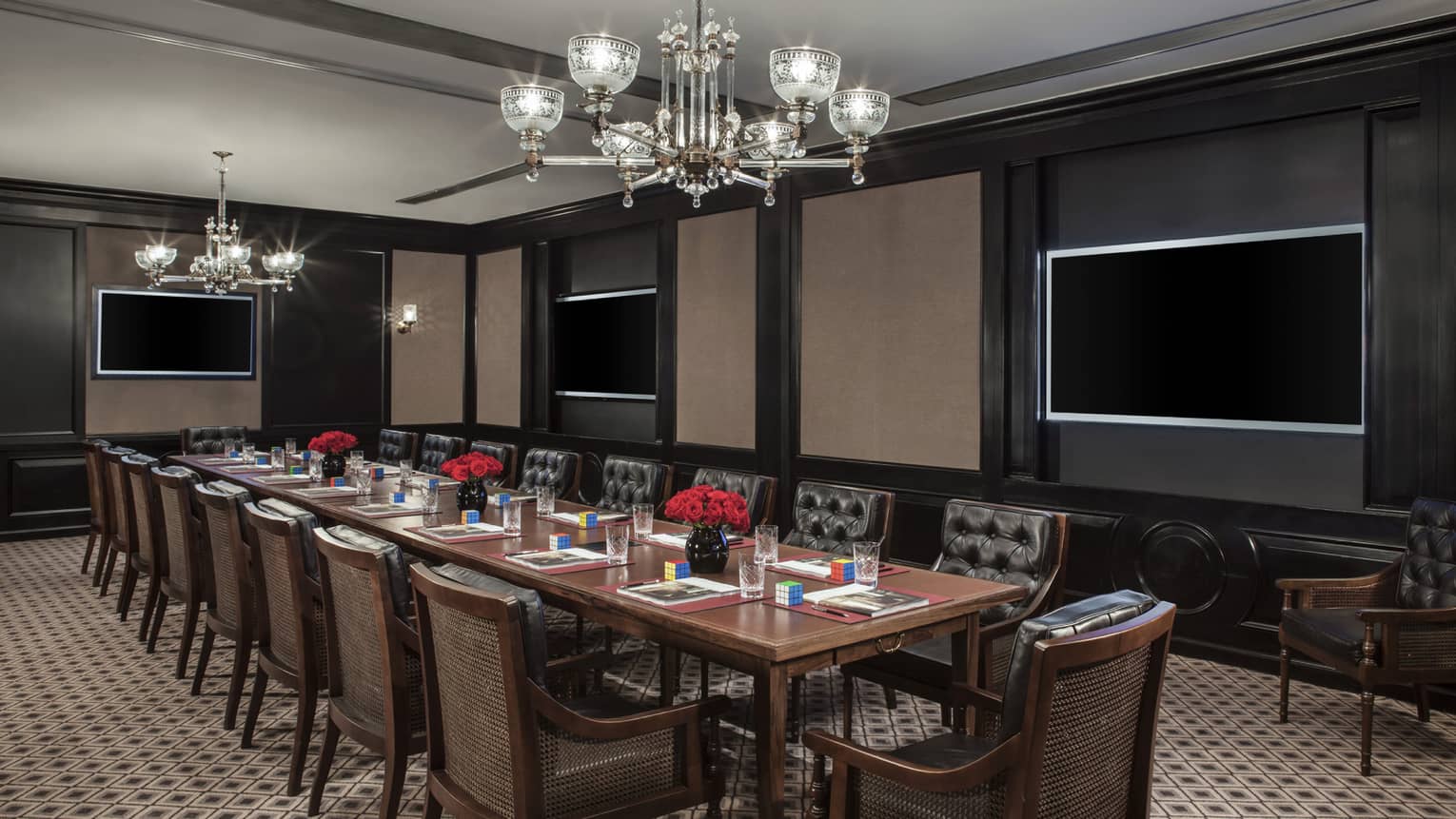 Greta Meeting Room long boardroom table under chandelier, three TV screens on walls