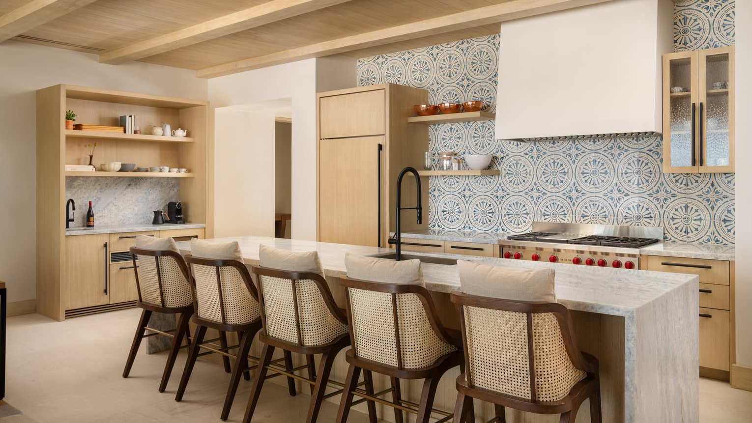 Luxury villa kitchen with mosaic tiled wall and marble island with five bar seats at Four Seasons Resort Cabo San Lucas at Cabo Del Sol