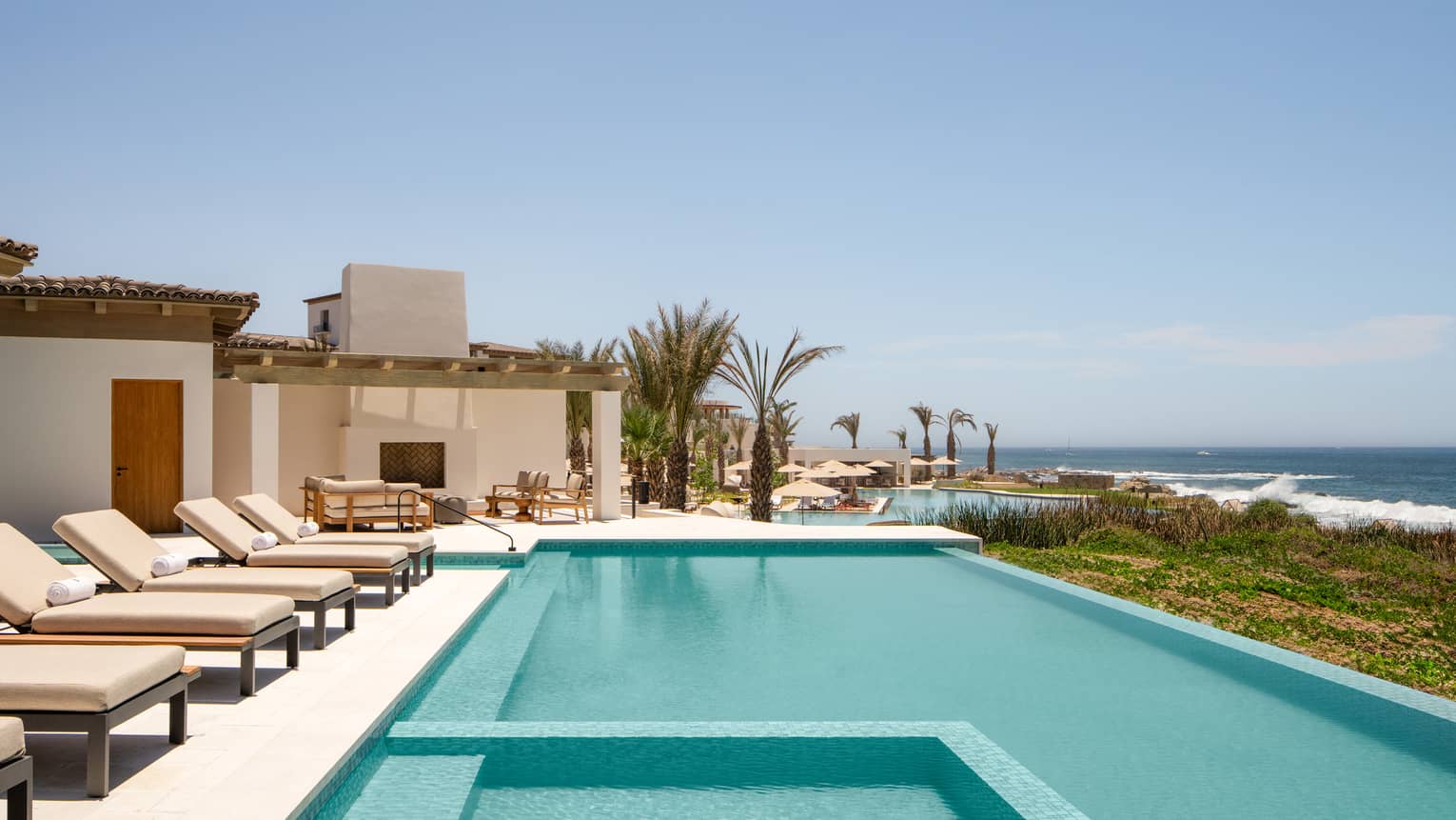 Large pool and sun loungers on a private villa terrace overlooking the sea