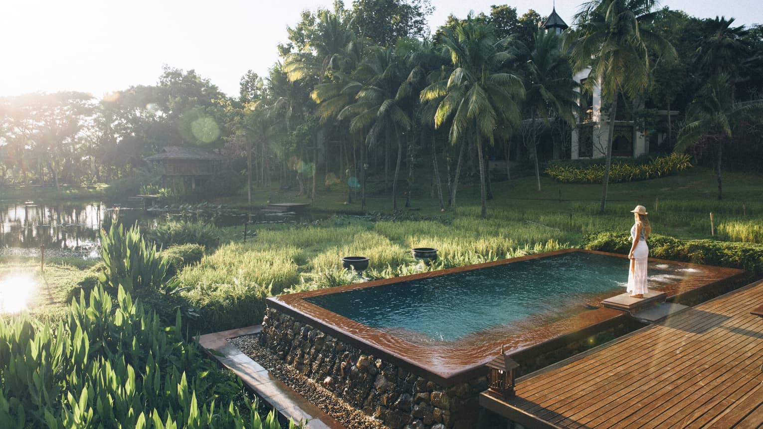 Woman stands at edge of infinity pool overlooking the rice paddies
