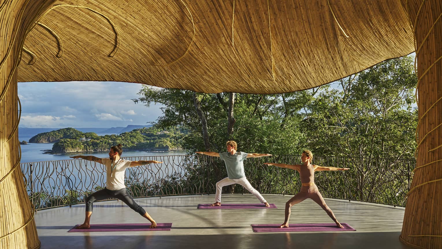 Two guests and an instructor practice yoga in the outdoor Wellness Shala