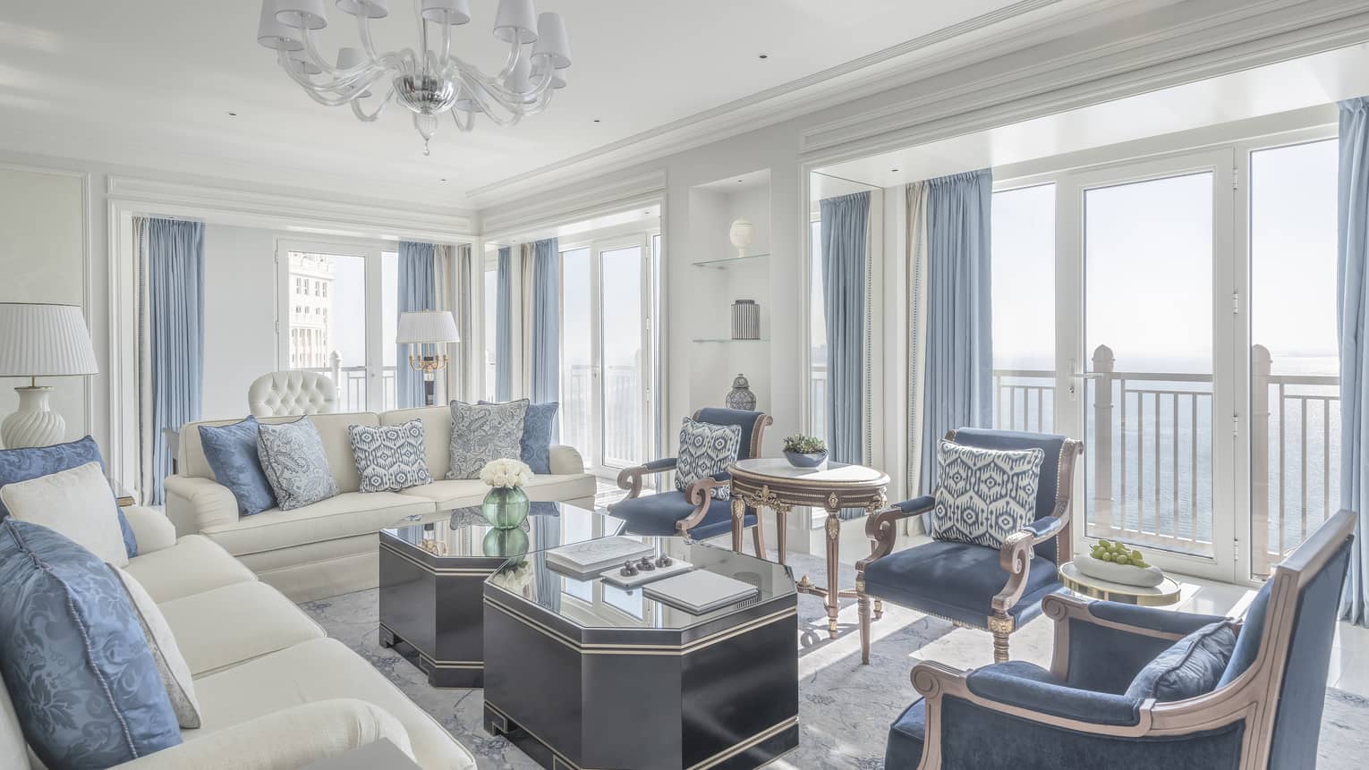 Living room with two white sofas, three blue arm chairs, blue curtains, two coffee tables