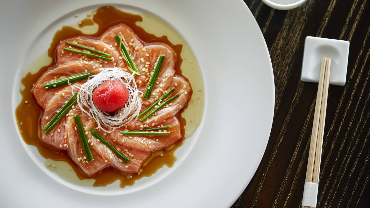 Aerial view of sashimi arranged as flower in dish, sauce and garnish
