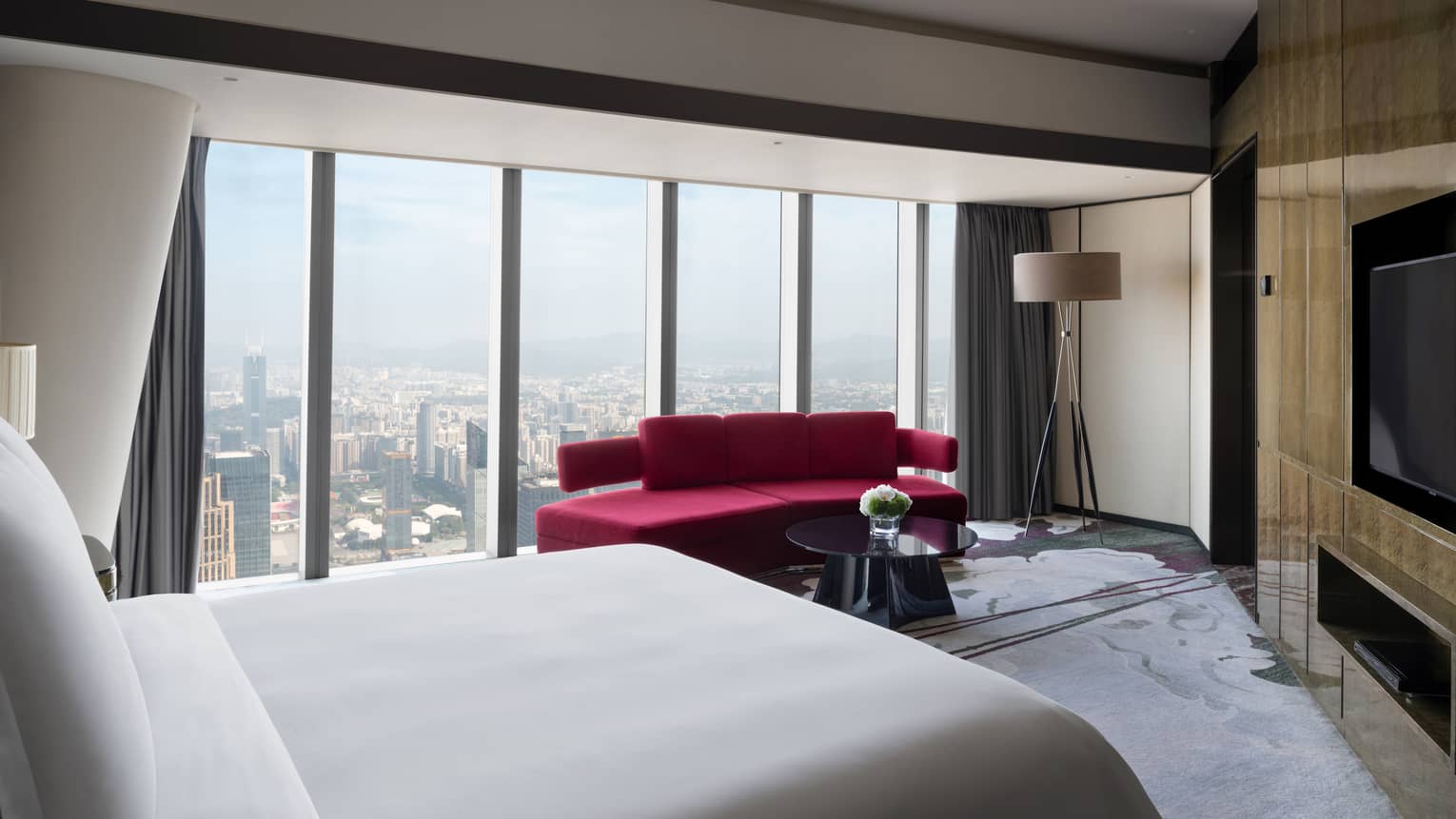 Deluxe King Suite City View Room with red sofa and floor-to-ceiling windows