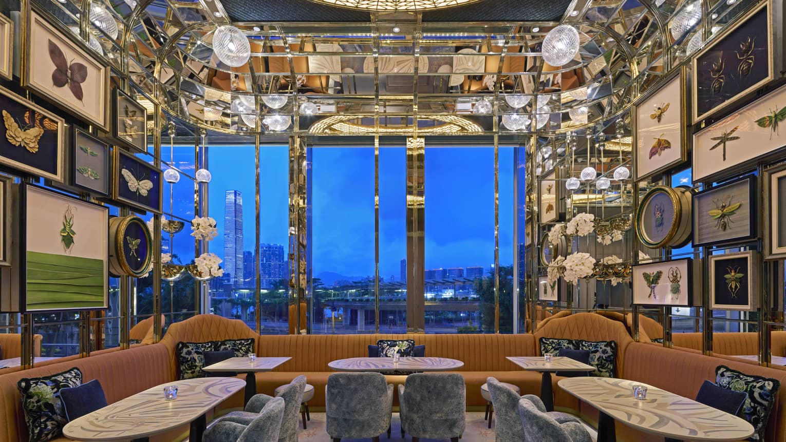 Lounge area with burnt orange booths, grey velvet chairs, walls filled with pictures