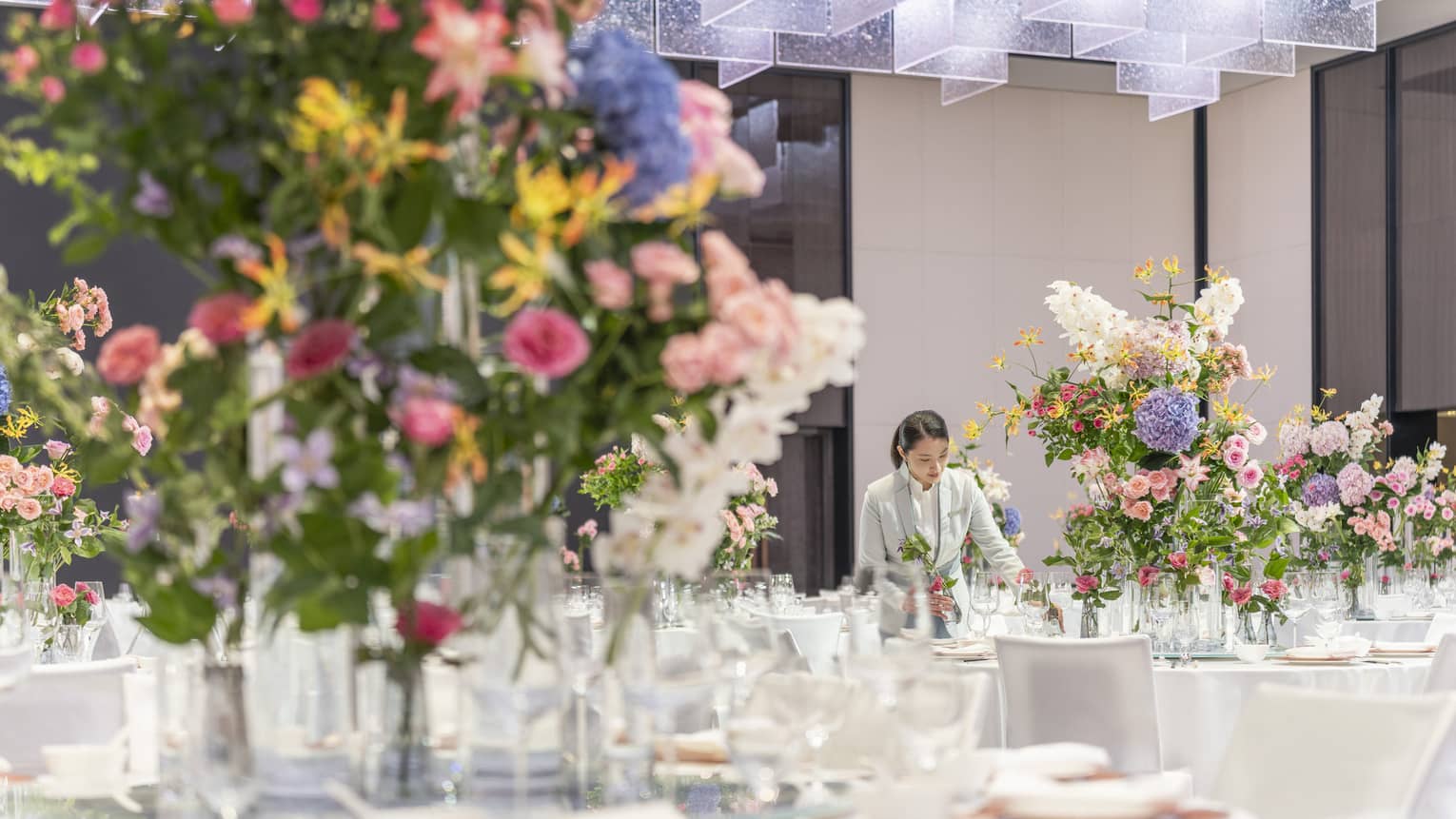 A ballroom set for an event with banquet tables featuring large colourful floral arrangements