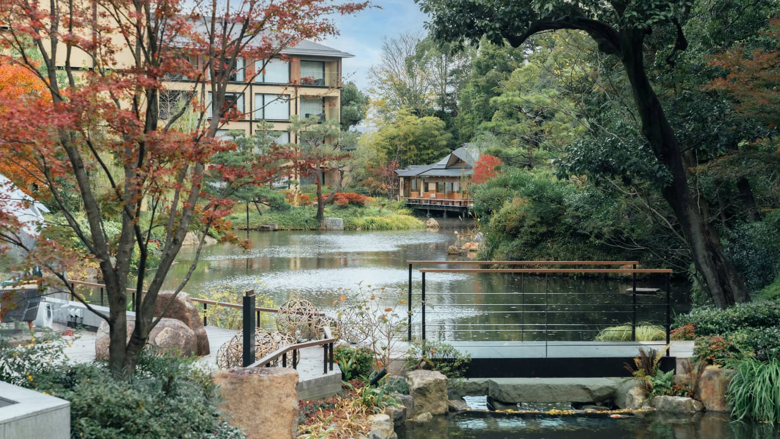 A pond surrounded by trees and crossed by a foot bridge