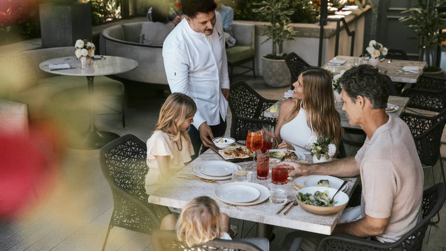 Family of four dines at a table on a restaurant terrace