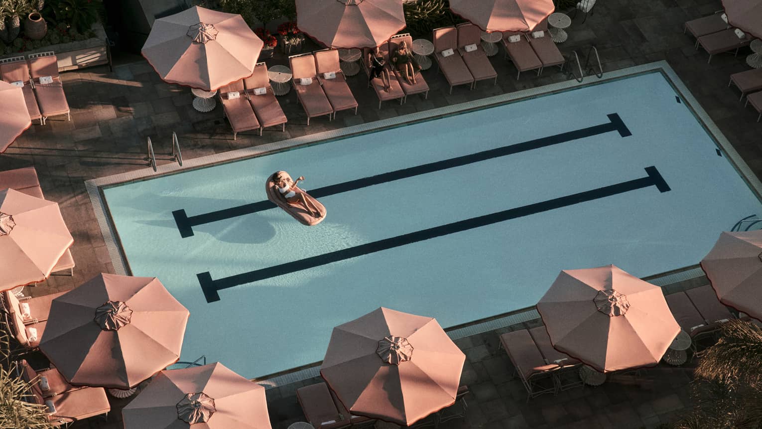 Hotel pool surrounded by pink umbrellas