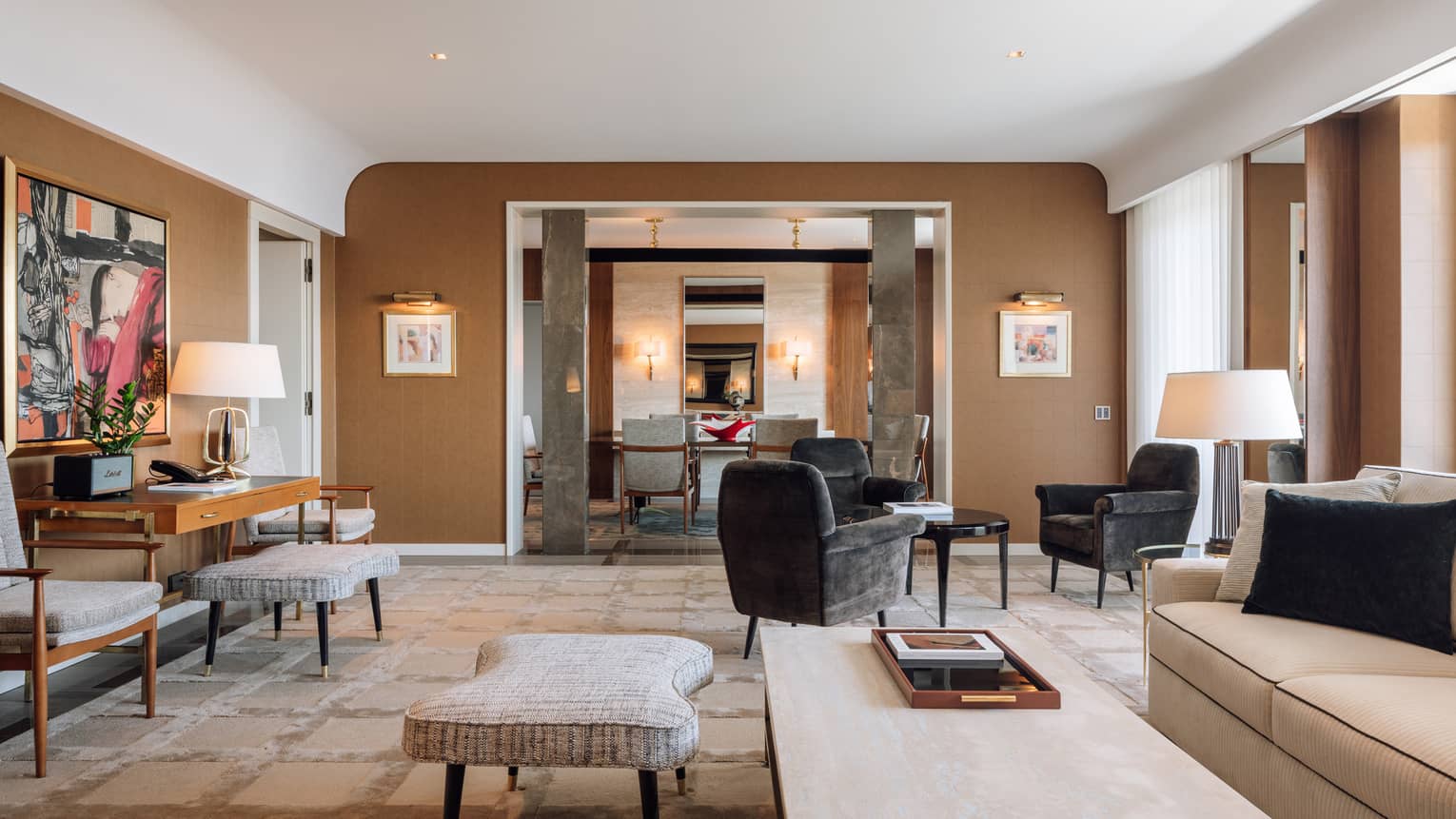 Interior living room of a hotel suite, featuring a sofa, coffee table, small round table with three arm chairs and desk