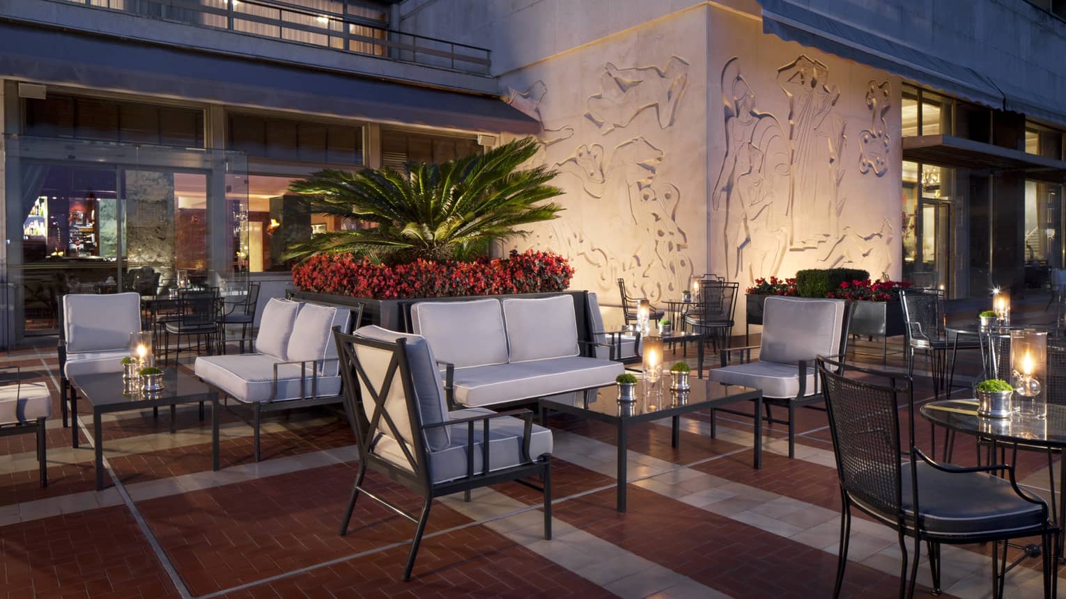 Ritz Bar outdoor patio lounge at night with cushioned chairs and loveseats around candle-lit cocktail tables