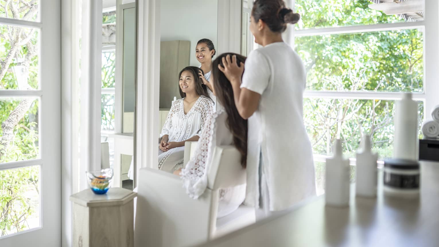 Person enjoying a hair treatment in a spa salon with large windows, surrounded by lush greenery