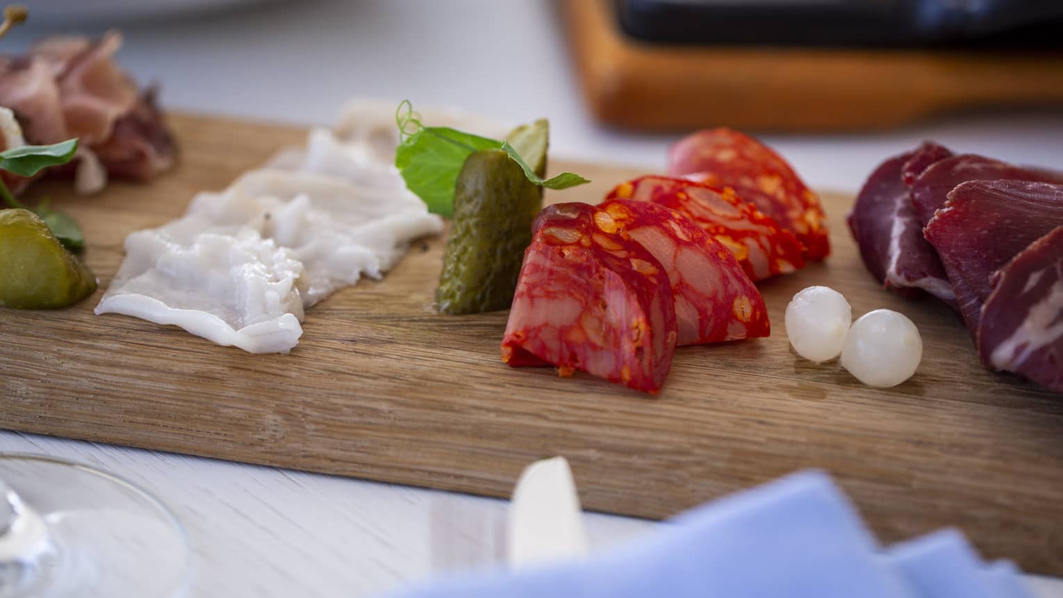 A charteurtie board with salami, cheese and onions on a table