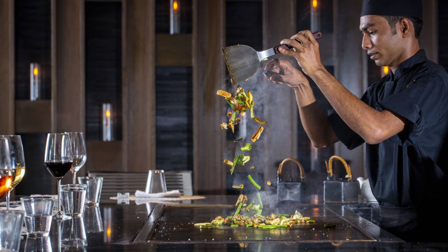  A four seasons dining staff working on a towering dish made of vegetables at the bar