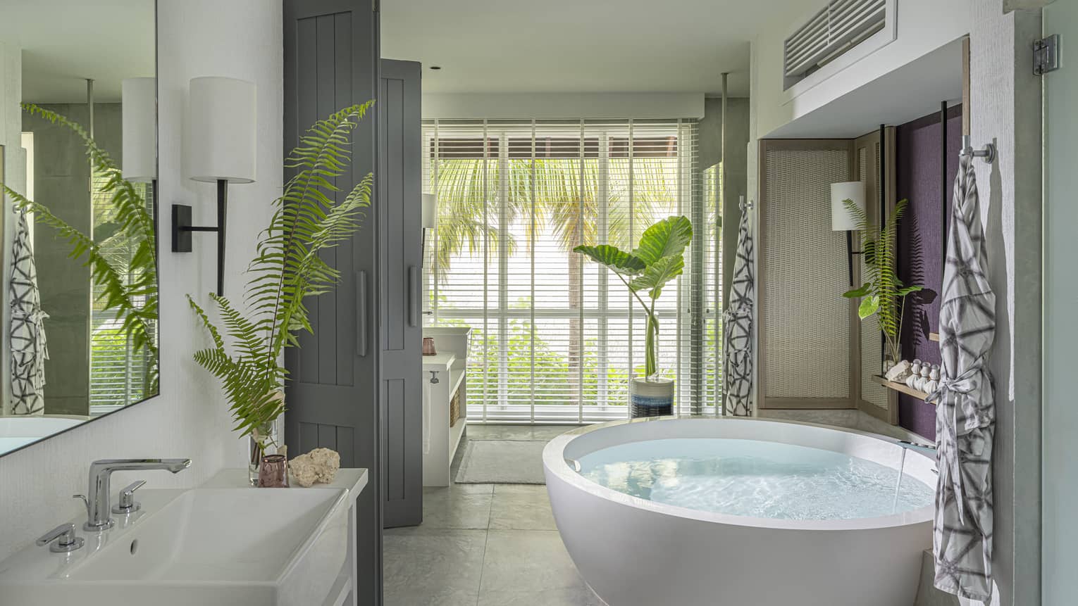 Luxury resort bathroom with free-standing circular tub and garden window view