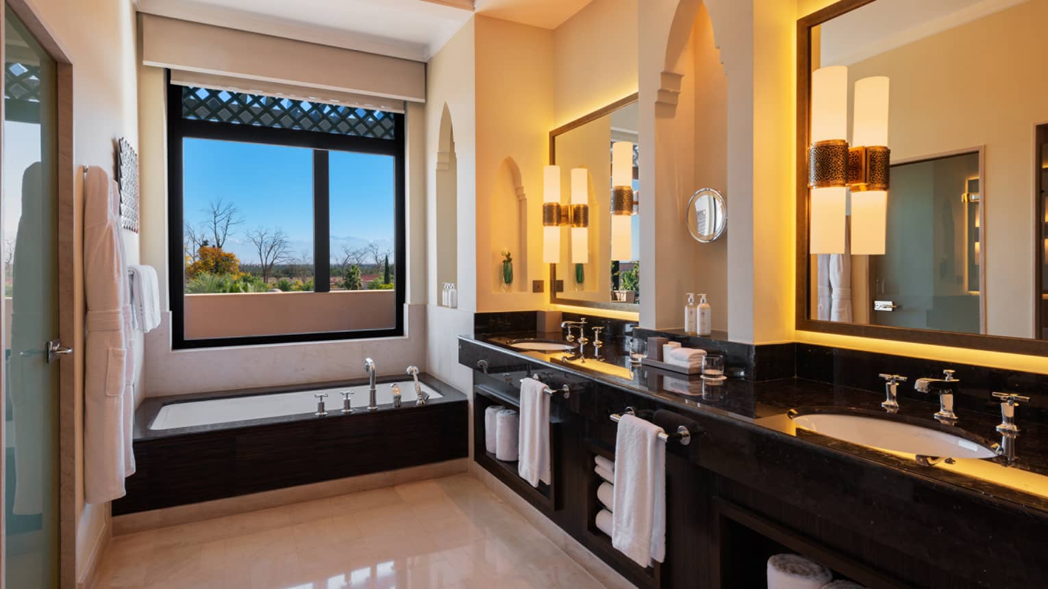 Luxury hotel bathroom with double vanity, sunken tub and window