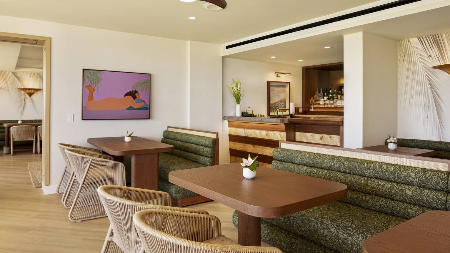 Wooden dining tables in an executive club lounge, featuring large green booths and woven beige chairs