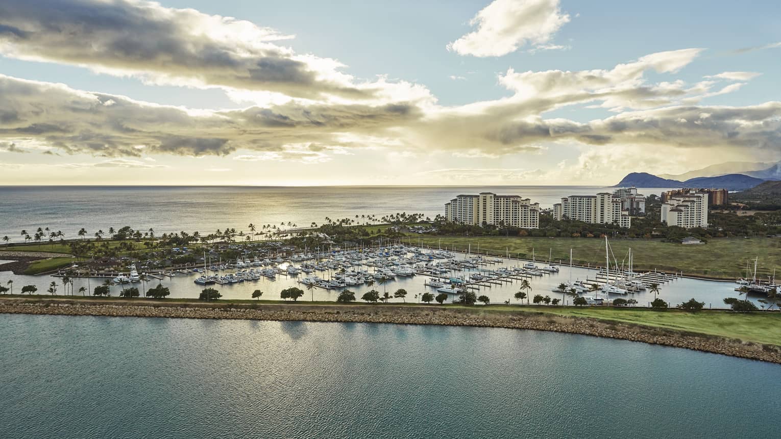 Aerial view of harbour lined with yachts, resort buildings at sunset