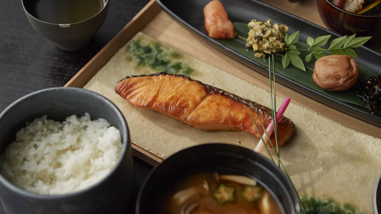 A Japanese style breakfast with rice, soup and grilled salmon.