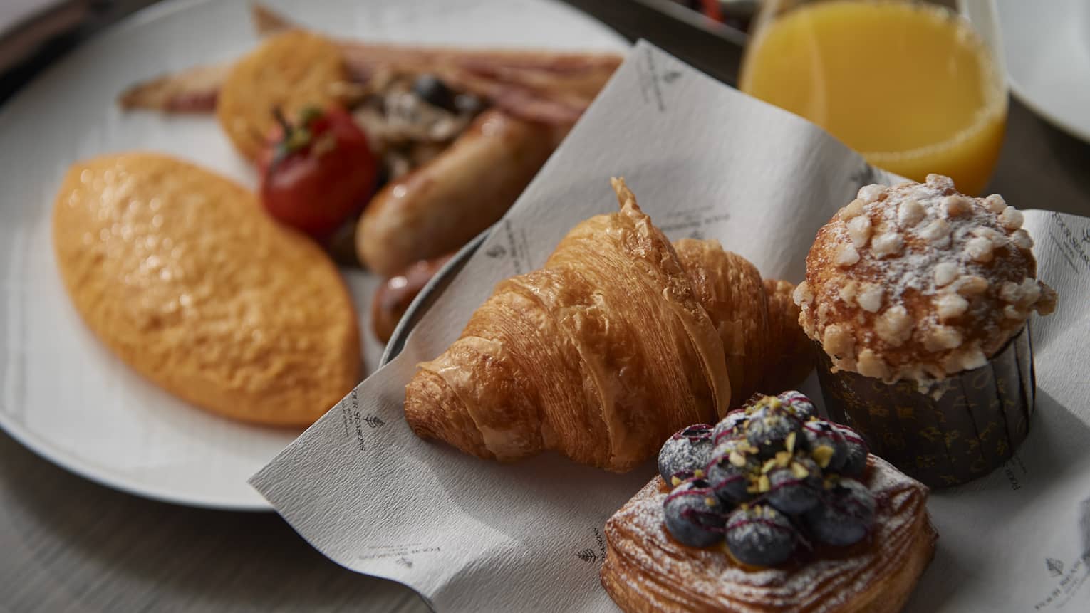 In-room dining breakfast spread with bakery items and orange juice